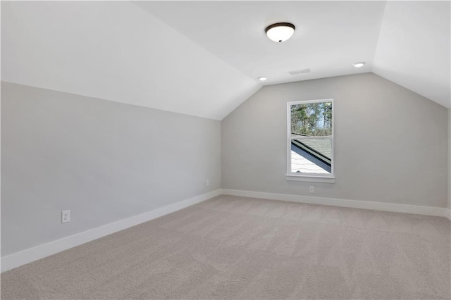 bonus room featuring vaulted ceiling, light colored carpet, and baseboards