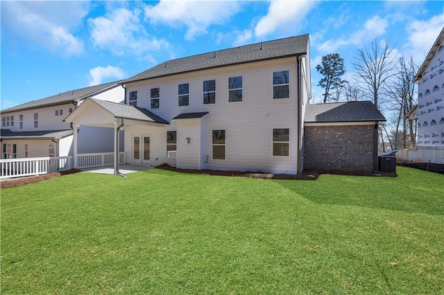 rear view of property featuring brick siding, fence, a patio, and a yard