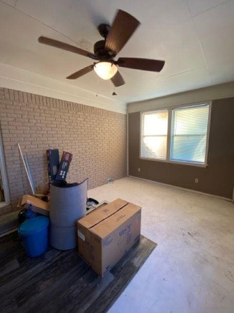 misc room with ceiling fan, brick wall, and concrete floors