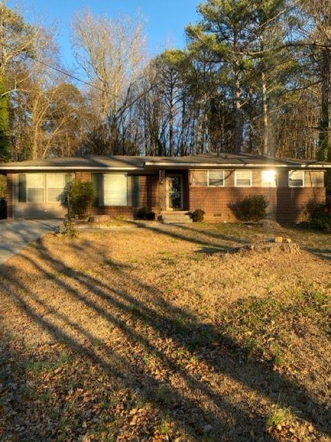 single story home featuring a front yard, a garage, and a carport