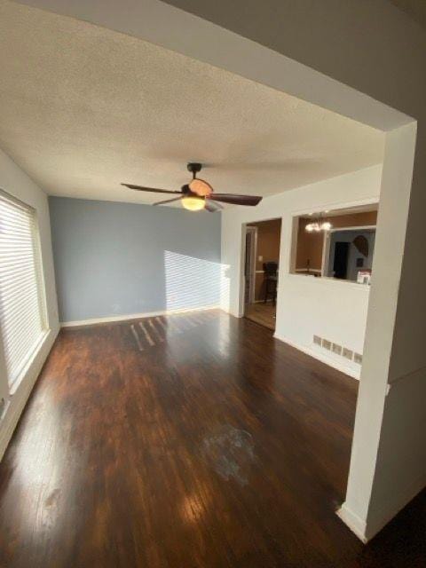 unfurnished living room featuring ceiling fan, dark hardwood / wood-style flooring, and a textured ceiling