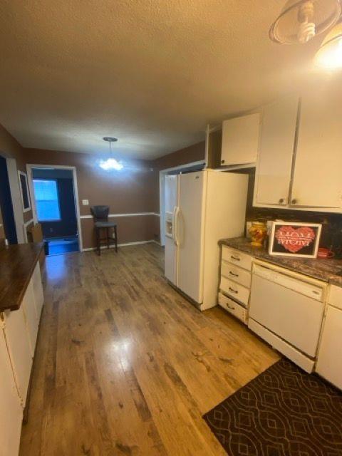 kitchen with white cabinetry, hardwood / wood-style flooring, decorative light fixtures, and white appliances