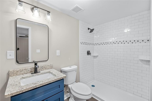 bathroom featuring vanity, toilet, and tiled shower