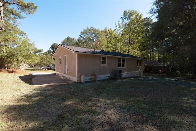 rear view of house featuring central AC and a lawn