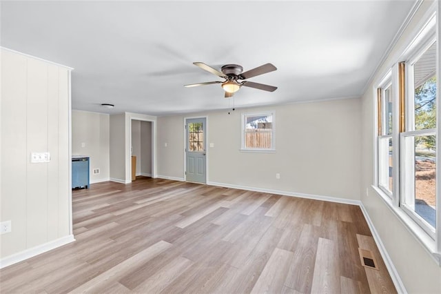 empty room featuring a wealth of natural light, ornamental molding, and light hardwood / wood-style floors