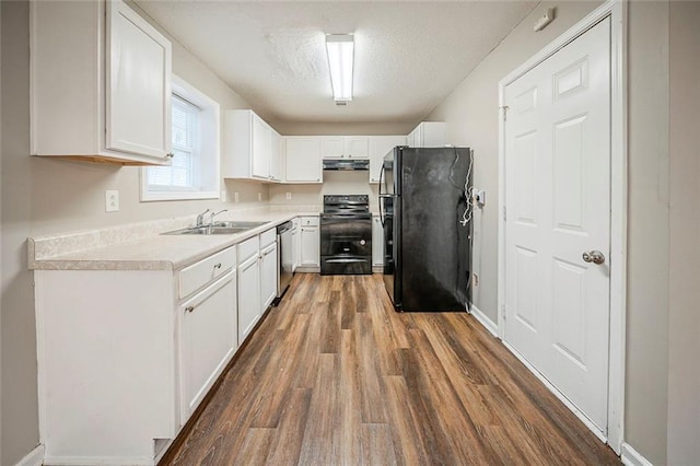 kitchen with extractor fan, wood finished floors, white cabinetry, light countertops, and black appliances