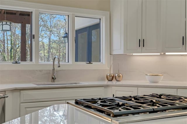 kitchen featuring tasteful backsplash, white cabinetry, and a sink