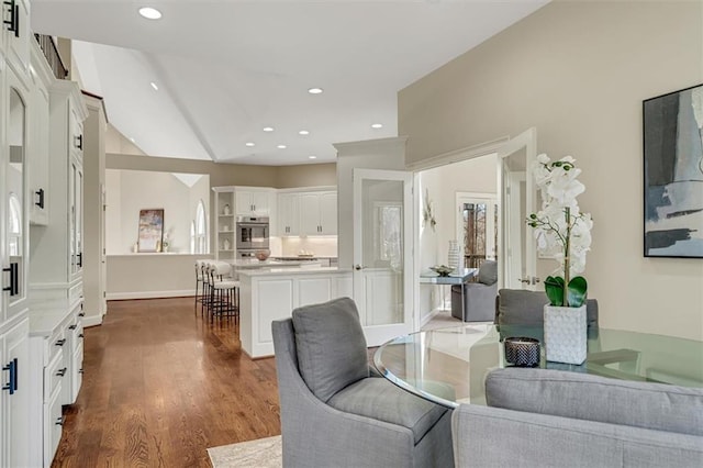 living area featuring baseboards, vaulted ceiling, dark wood-style flooring, and recessed lighting