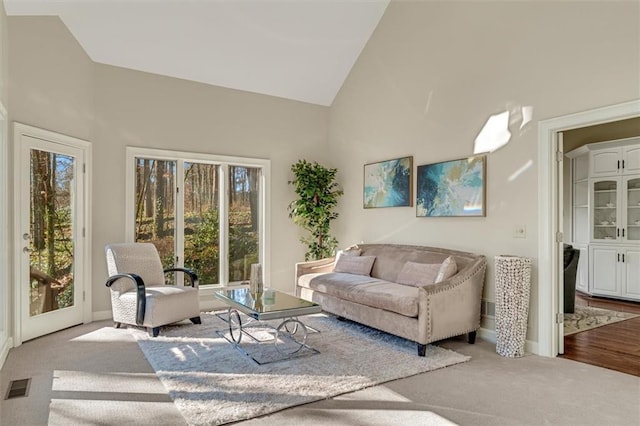 living room featuring high vaulted ceiling, visible vents, and carpet flooring