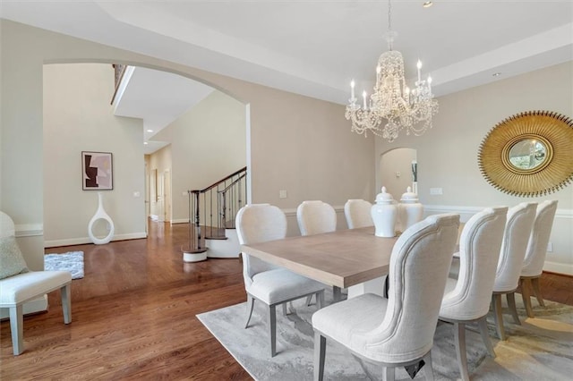 dining area with stairway, baseboards, arched walkways, and wood finished floors