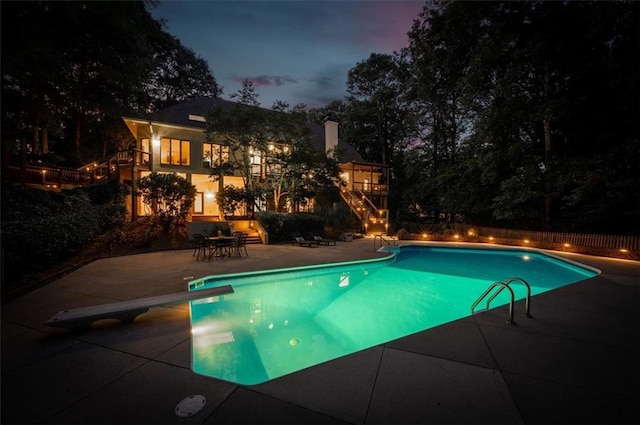 pool with stairs, a patio, and a diving board