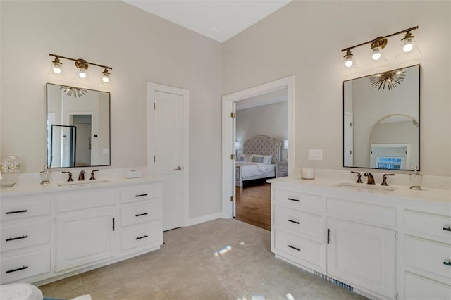 bathroom with ensuite bath, two vanities, and a sink