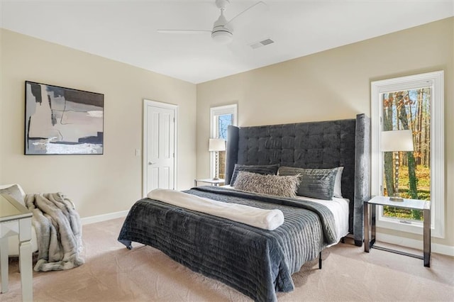 carpeted bedroom featuring a ceiling fan, visible vents, and baseboards