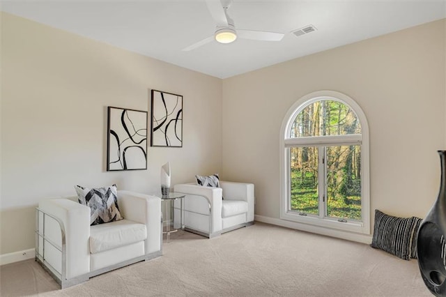 living area featuring baseboards, visible vents, a ceiling fan, and carpet flooring