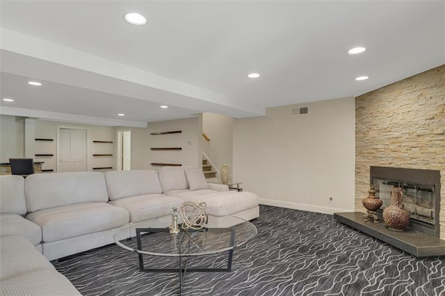 carpeted living area with a stone fireplace, recessed lighting, visible vents, and baseboards