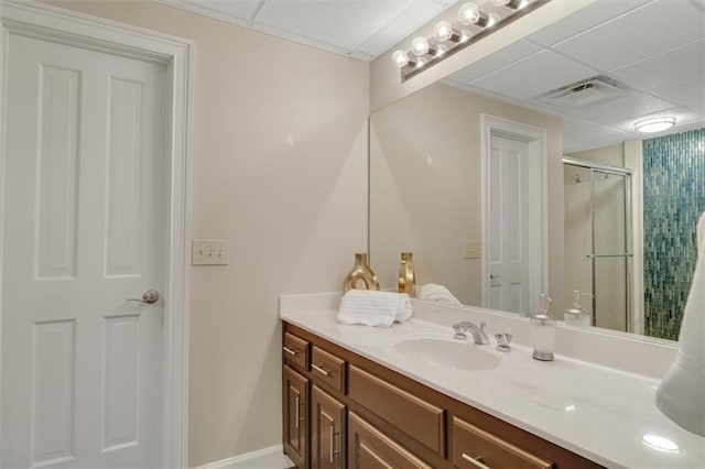 bathroom with a shower stall, visible vents, a drop ceiling, and vanity