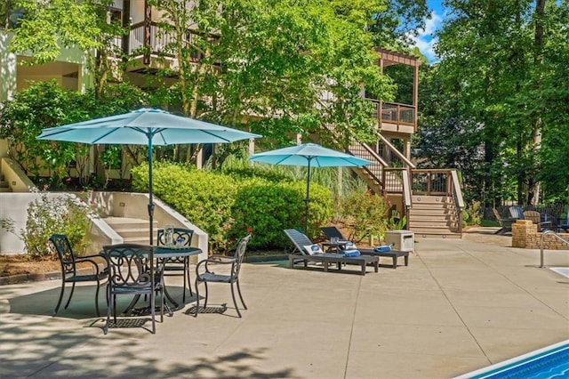 view of patio featuring a deck, outdoor dining space, and stairway