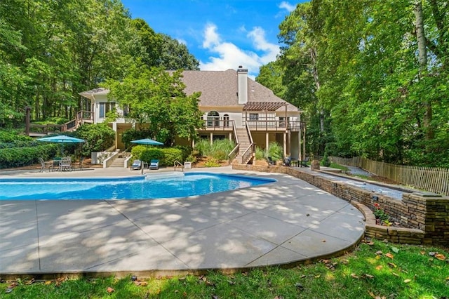 outdoor pool featuring a patio area, fence, stairway, and a deck