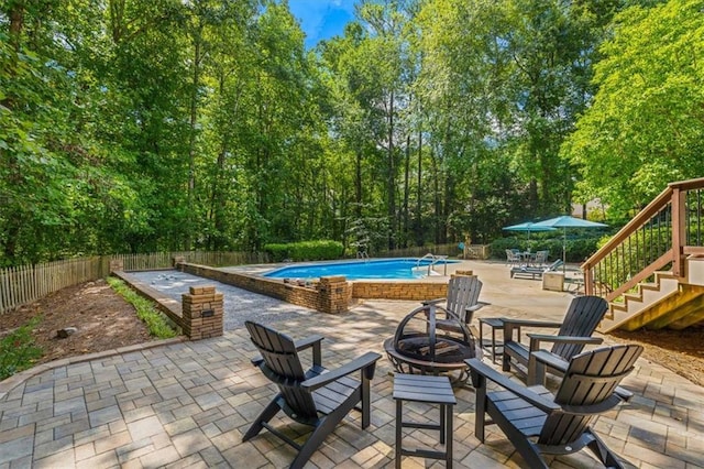 view of patio with an outdoor fire pit, fence, and a fenced in pool