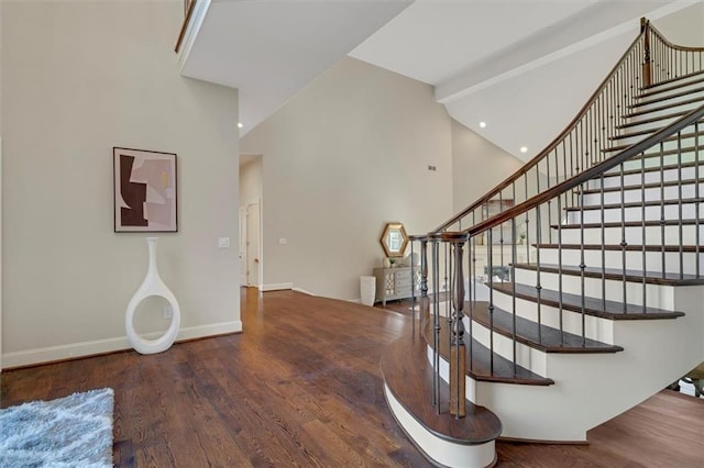 stairs featuring recessed lighting, a towering ceiling, baseboards, and wood finished floors