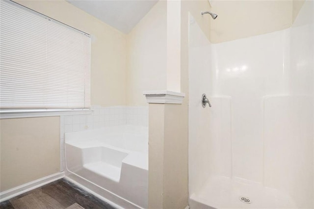 full bathroom featuring a stall shower, baseboards, a bath, and wood finished floors