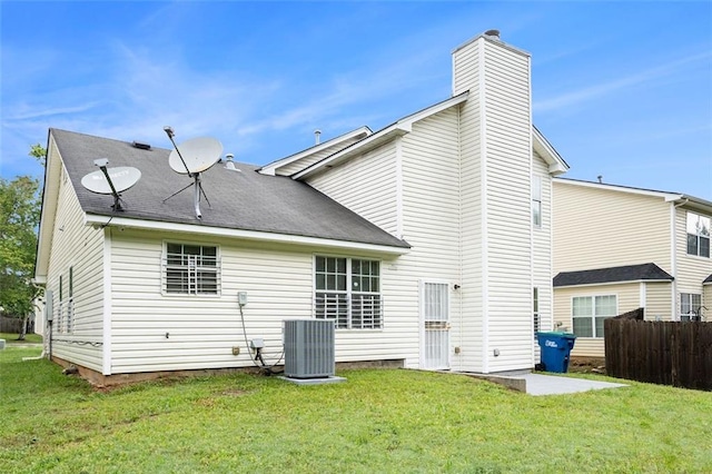 back of house featuring a chimney, cooling unit, a yard, and fence