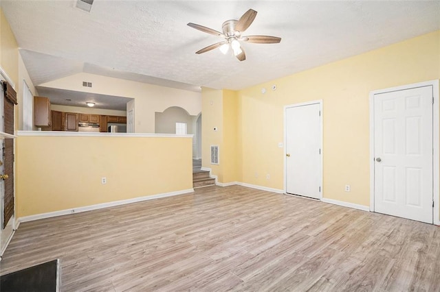 unfurnished living room with baseboards, visible vents, ceiling fan, arched walkways, and light wood-type flooring