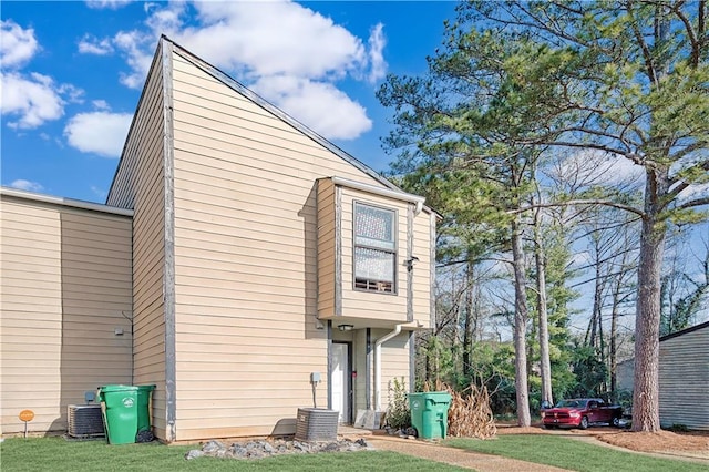 back of house featuring central AC unit and a lawn