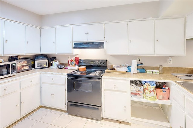 kitchen with light tile patterned floors, black / electric stove, and white cabinetry