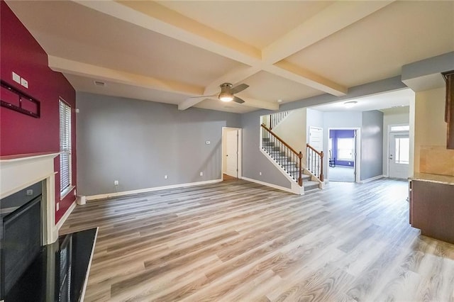 unfurnished living room with coffered ceiling, ceiling fan, beamed ceiling, and light wood-type flooring