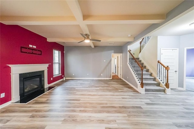 unfurnished living room featuring coffered ceiling, ceiling fan, beam ceiling, and light hardwood / wood-style flooring