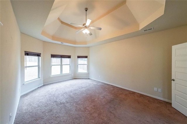 carpeted spare room with a tray ceiling and ceiling fan