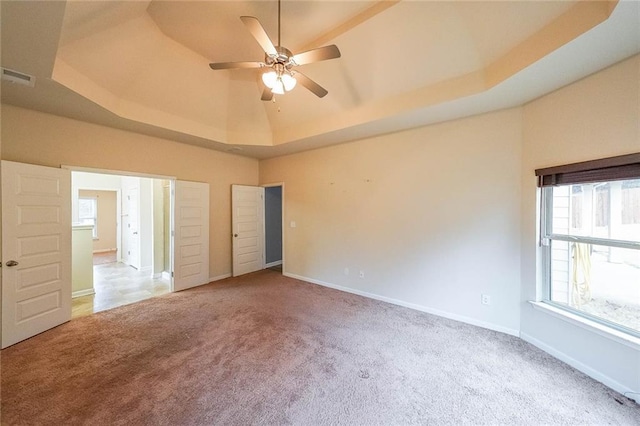 unfurnished bedroom featuring lofted ceiling, a raised ceiling, ceiling fan, and carpet flooring