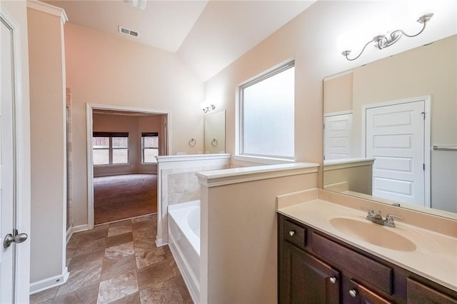 bathroom with vanity, a bath, and vaulted ceiling