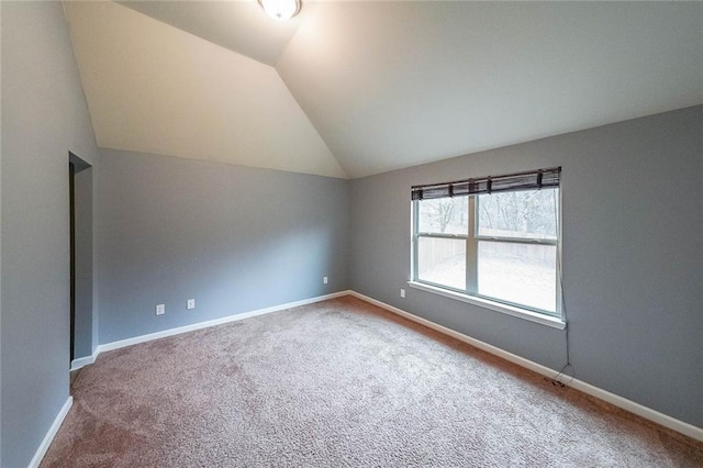 carpeted spare room with vaulted ceiling