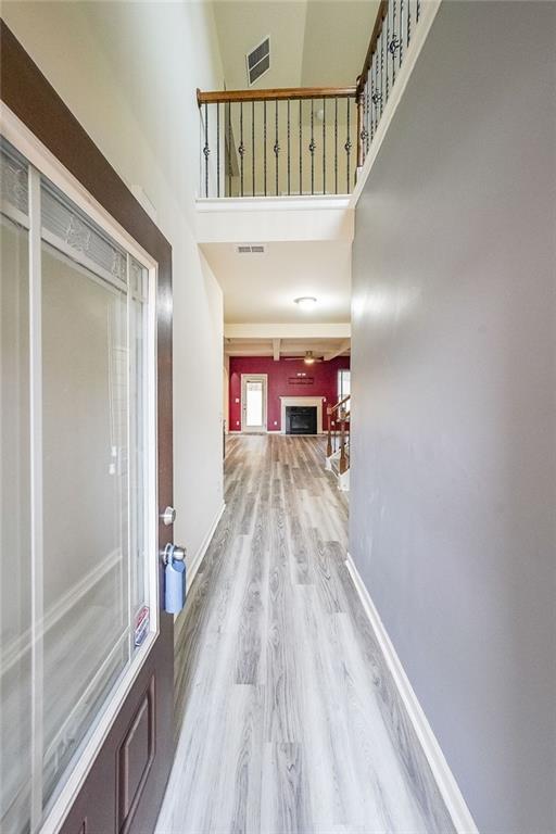 corridor with a towering ceiling and light hardwood / wood-style flooring