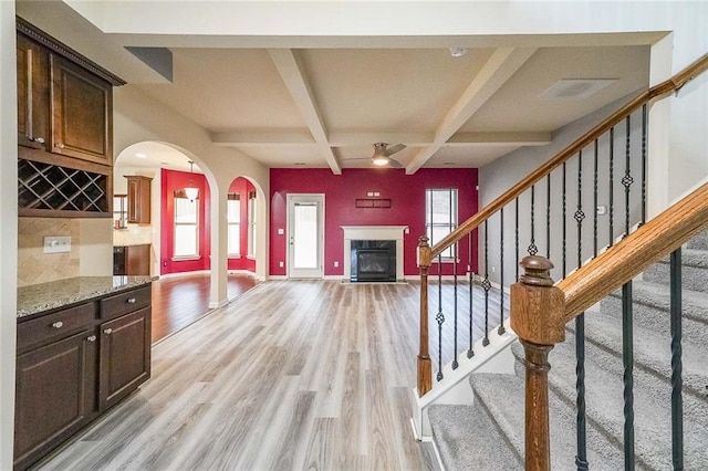 interior space featuring coffered ceiling, light stone counters, a healthy amount of sunlight, and light wood-type flooring