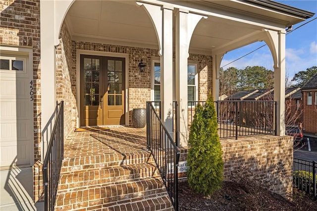 property entrance with an attached garage, french doors, and brick siding