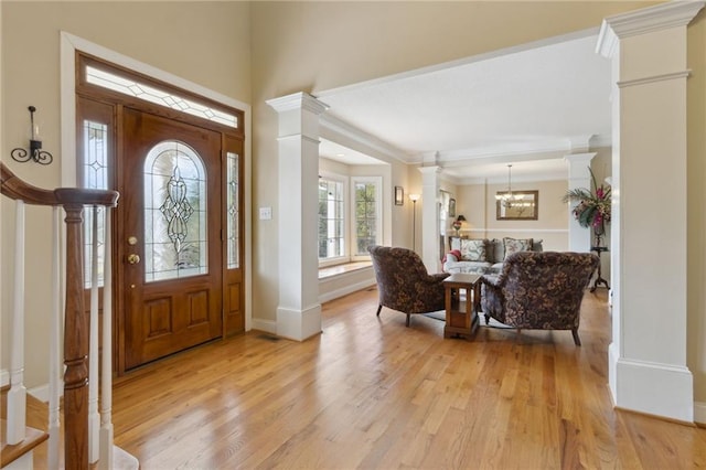 entryway featuring light wood finished floors, a notable chandelier, baseboards, and decorative columns