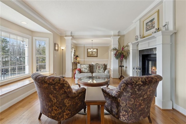 living room featuring crown molding, light wood finished floors, and ornate columns