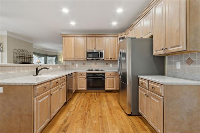 kitchen featuring light brown cabinets, a peninsula, light wood-style floors, stainless steel appliances, and a sink