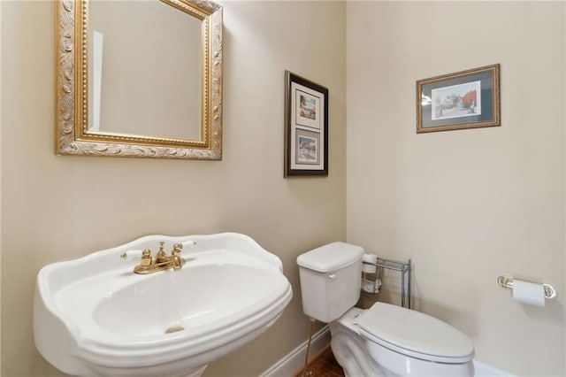 bathroom with toilet, baseboards, and a sink