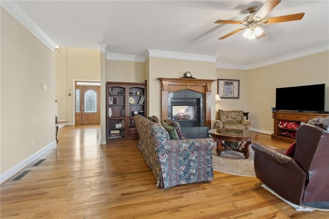 living room with ornamental molding, visible vents, and light wood-type flooring