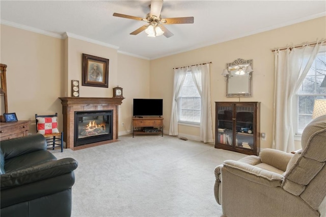 carpeted living area featuring a glass covered fireplace, baseboards, ceiling fan, and ornamental molding