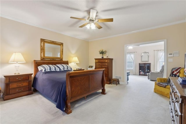 bedroom with visible vents, crown molding, baseboards, light colored carpet, and ceiling fan