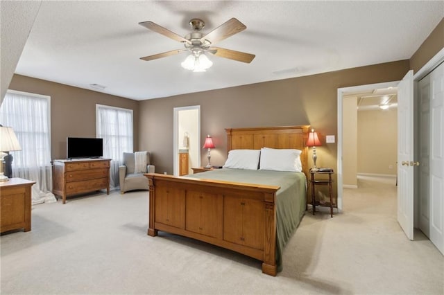 bedroom featuring connected bathroom, light colored carpet, baseboards, and ceiling fan