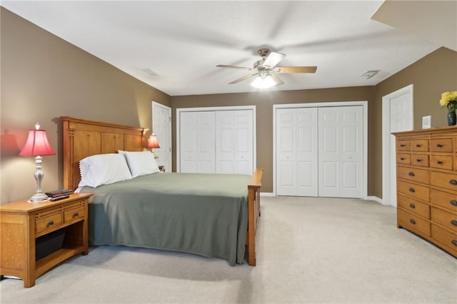 bedroom with light carpet, baseboards, a ceiling fan, and multiple closets