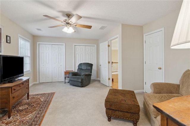 living area with light carpet, visible vents, ceiling fan, and baseboards