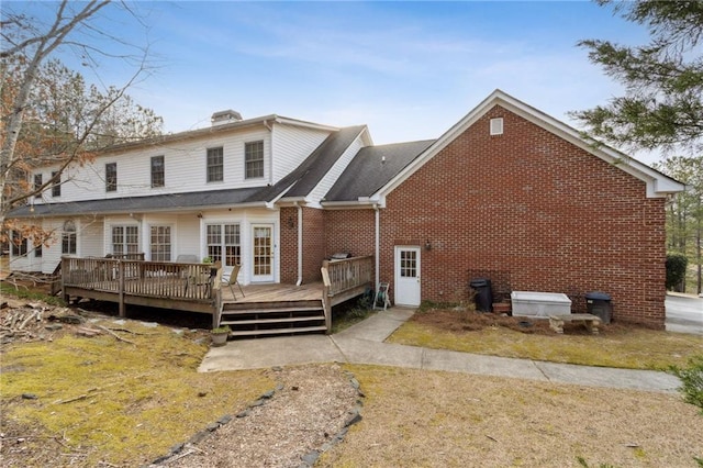 back of house featuring a deck, brick siding, and a chimney