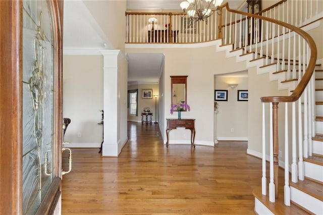 foyer entrance featuring stairs, wood finished floors, baseboards, and ornate columns